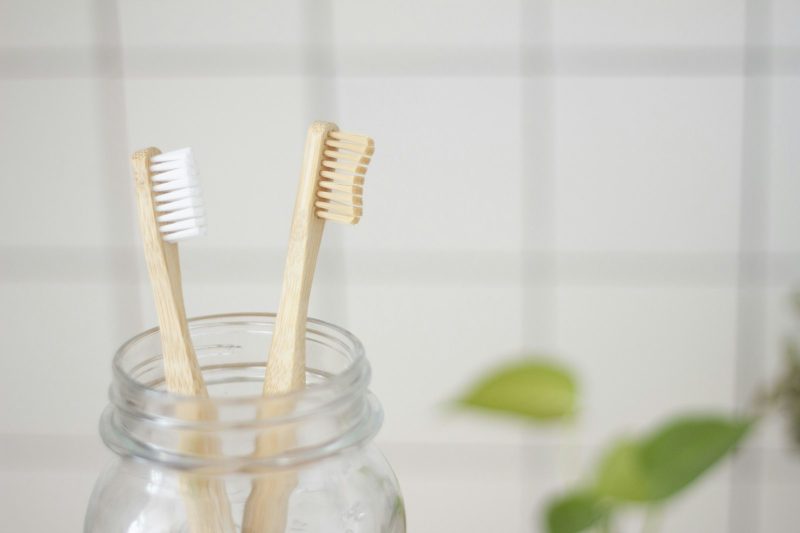 Two bamboo toothbrushes standing in a glass jar