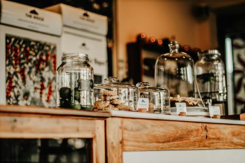 Glass jars of loose goods lined up on the wooden counter of a refill shop