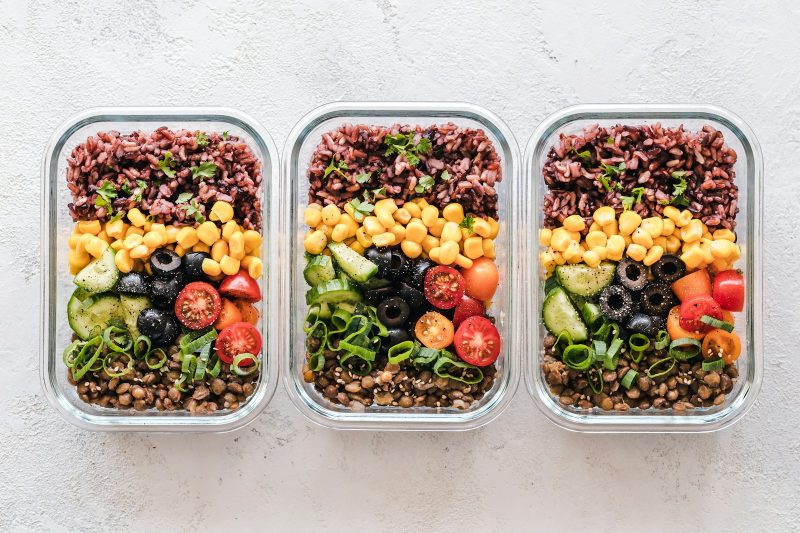 Three glass meal prep containers filled with grains, chickpeas and vegetables