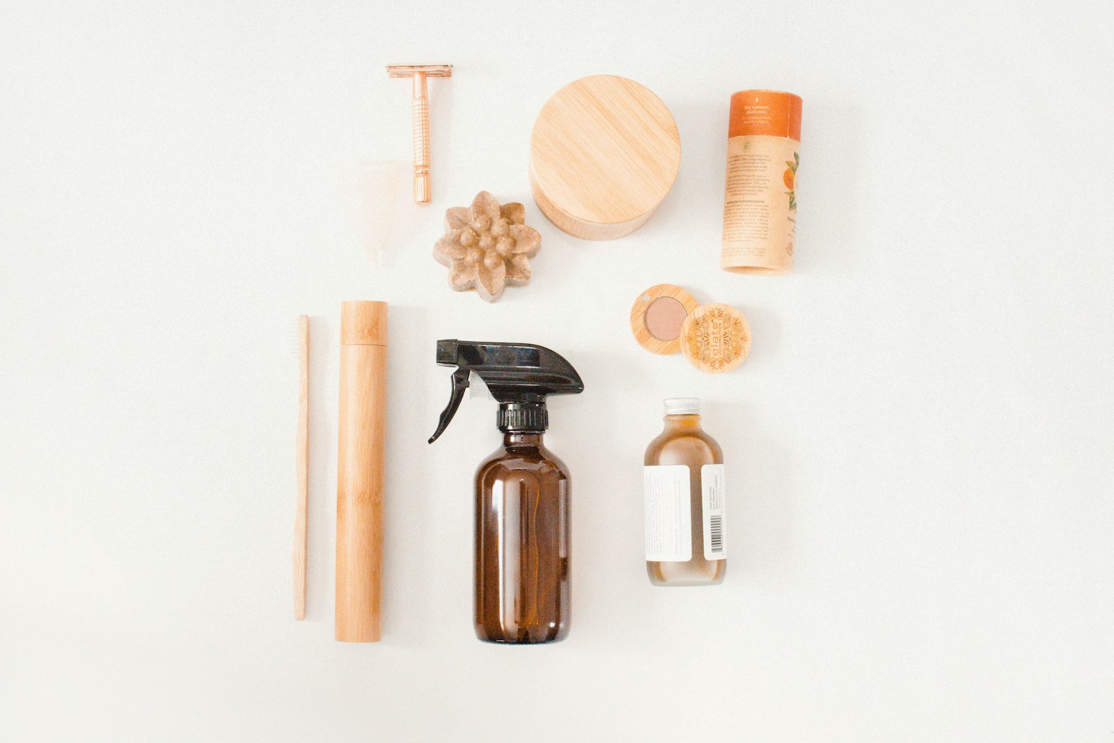 Flat lay of reusable household basics including an amber glass spray bottle and wooden and bamboo items