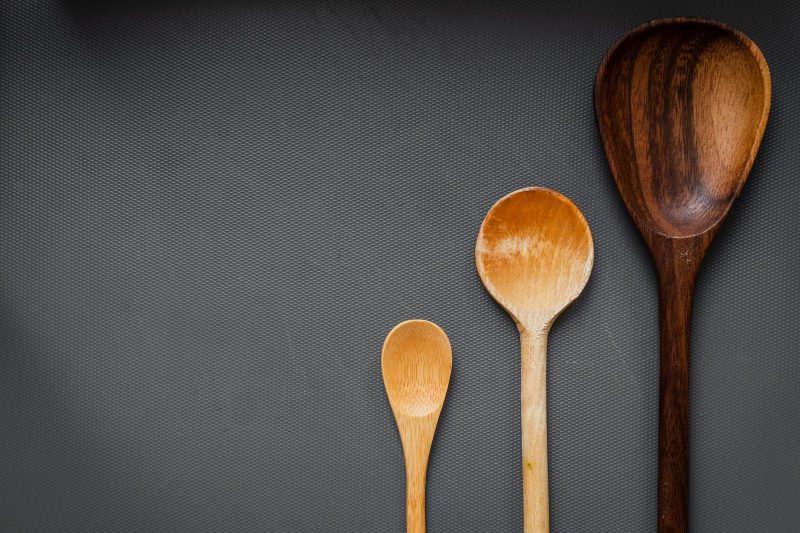 Three wooden spoons of different sizes on a dark grey surface