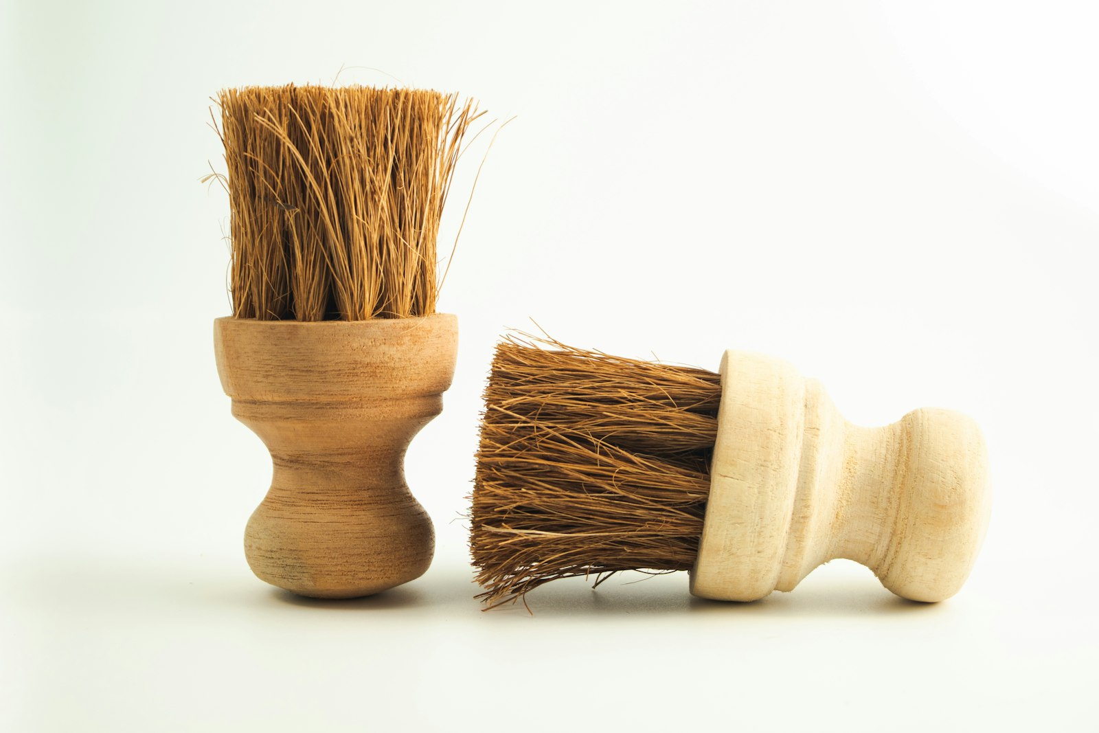 Two wooden-handled natural-bristle scrubbing brushes on a white background