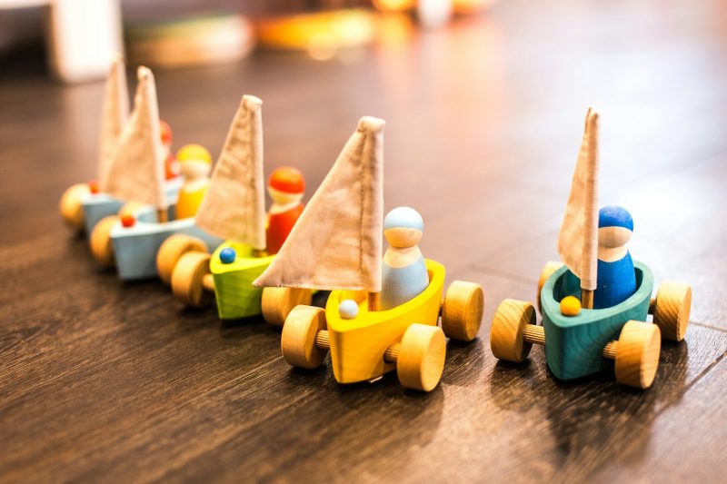 Colourful wooden toy boats with small peg figures on a wooden table