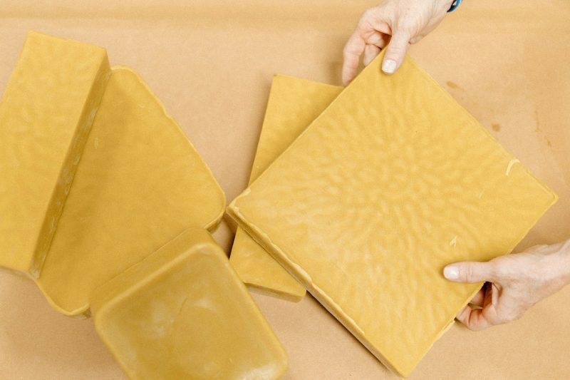 Hands laying out yellow beeswax food wraps in different sizes