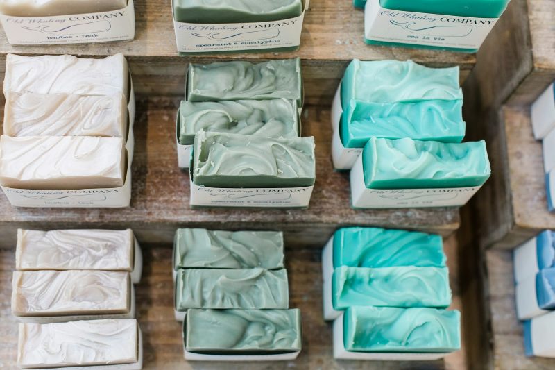 Handmade bar soaps in white and green stacked on wooden shelves